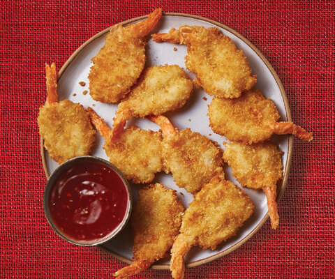 Prepared Panache Breaded Shrimp with a complementary sauce on a white plate.